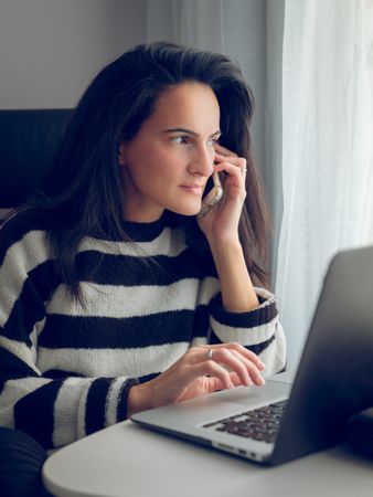 Self employed woman having phone call during online work