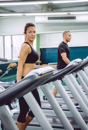 Fit male and female working out on treadmills in gym