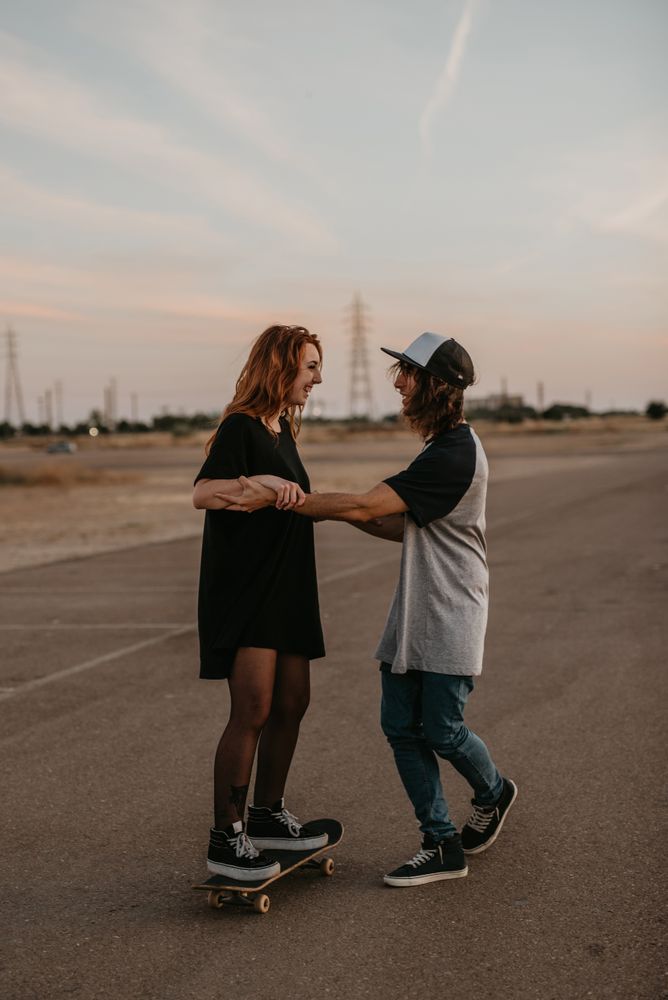 Man helping girlfriend to skate on road