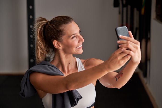 Smiling sportswoman taking selfie in gym
