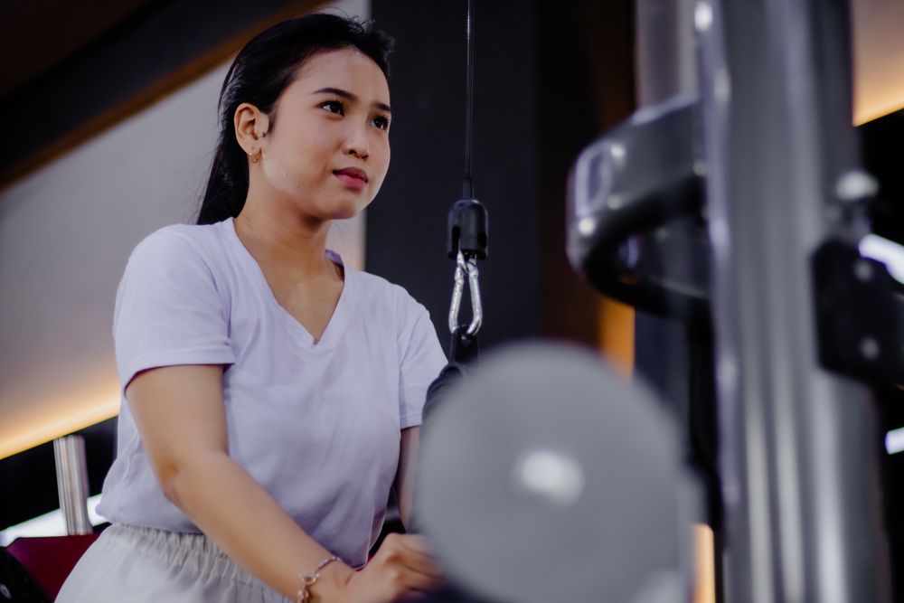 Focused young woman exercising with a lat pulldown machine indoo