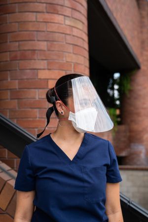 Close up profile of woman nurse wearing face shield and mask looking away