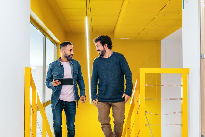 Two male coworkers working and talking in a coworking
