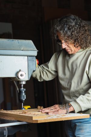 Woodworker using drilling machine in joinery