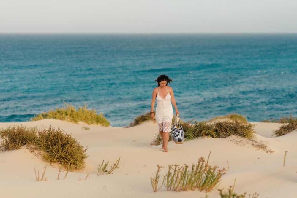 Active woman in white shorts walking sandy beach
