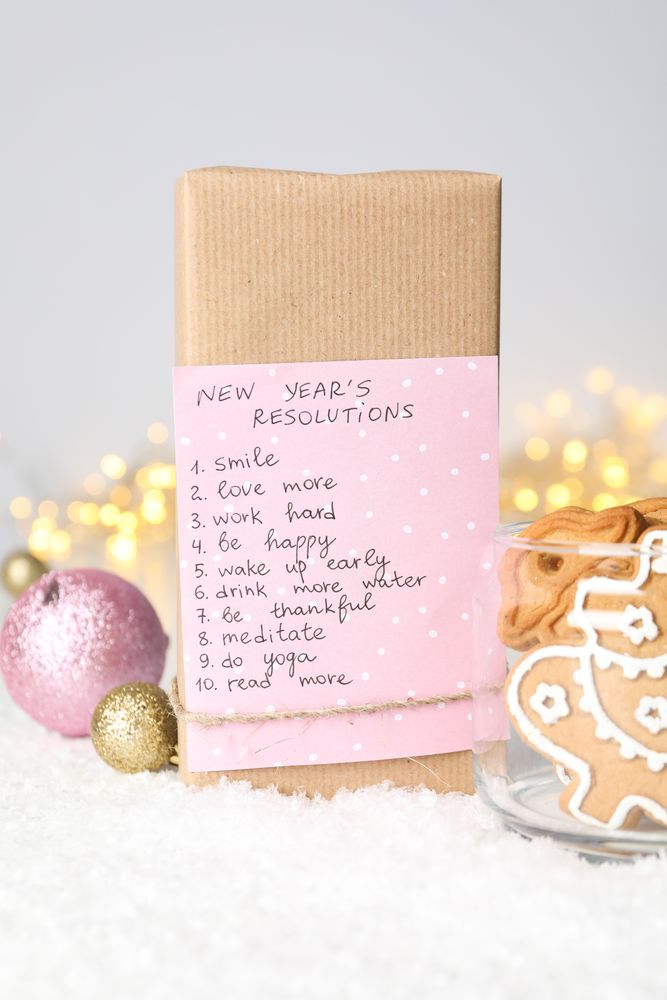 Cookies in jar and paper with list on box on light background