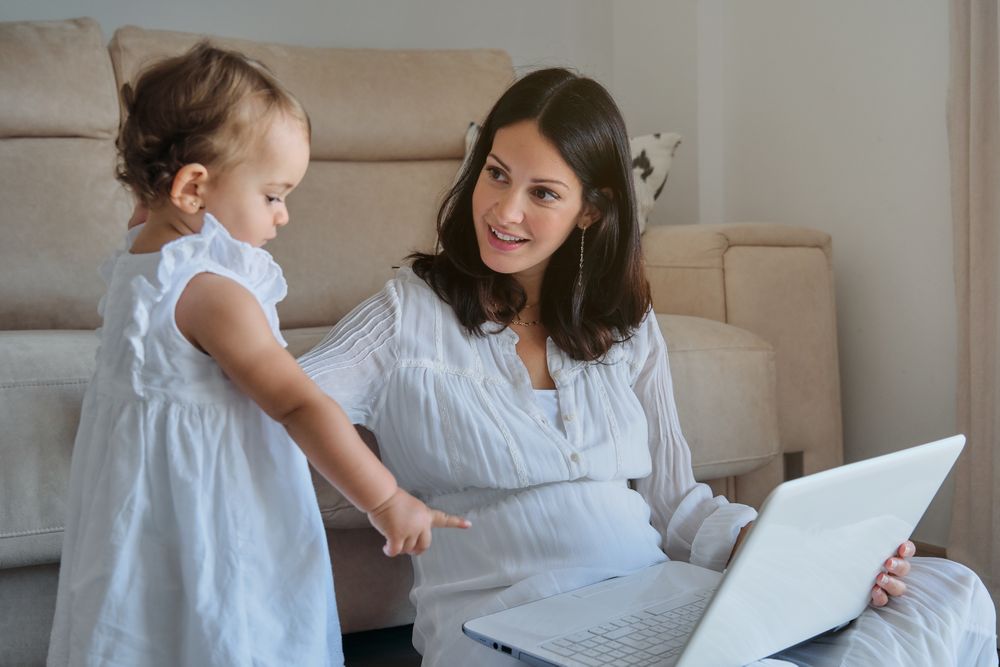 Mom with toddler working on laptop from home