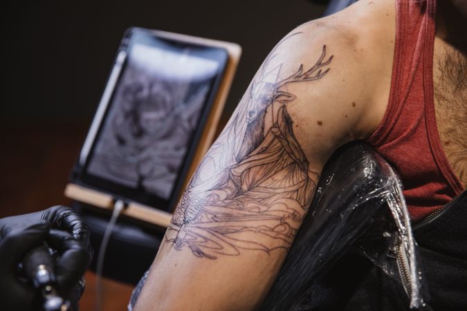 Master doing tattoo on forearm of male customer