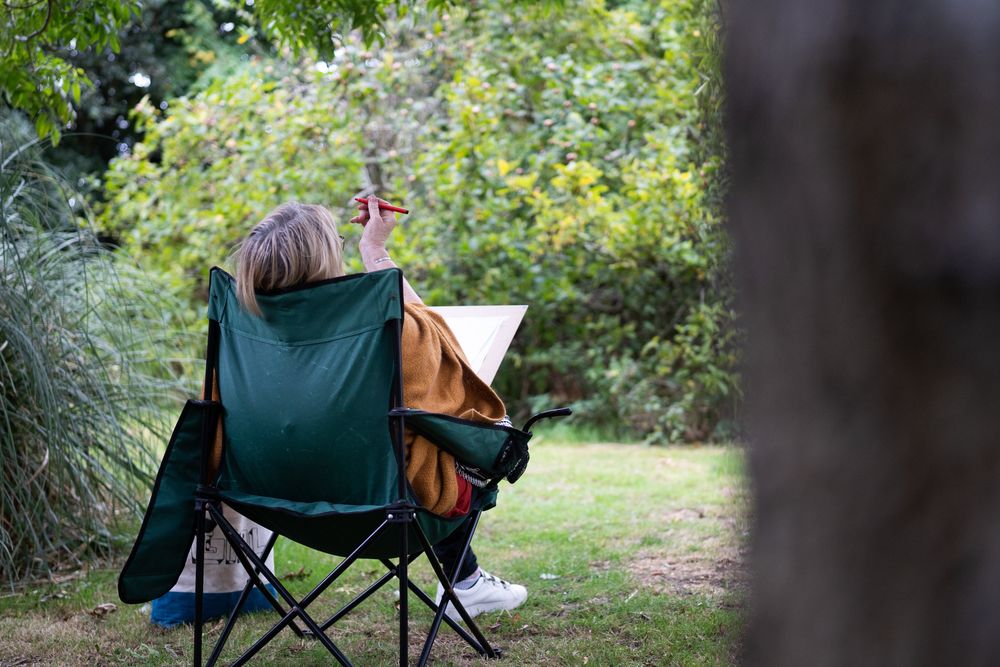 Back of woman sitting calmly outside drawing