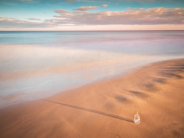 Bottle in sand near sea