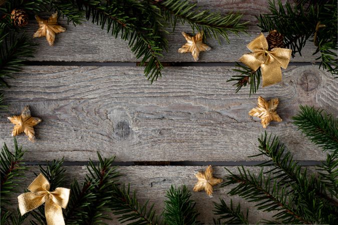 Pine branches bordering wooden background with gold ribbons