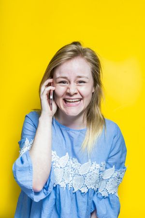 Excited young woman talking on smartphone