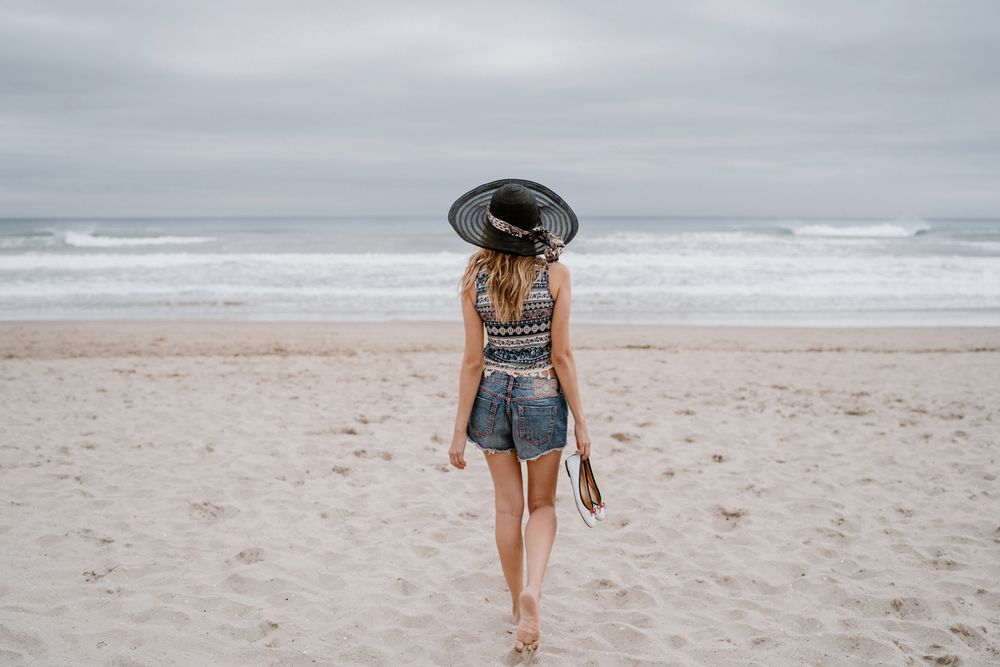 Young female walking barefoot on sandy beach