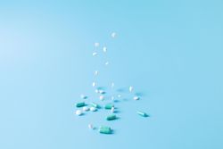 Variety of medications falling on blue backdrop