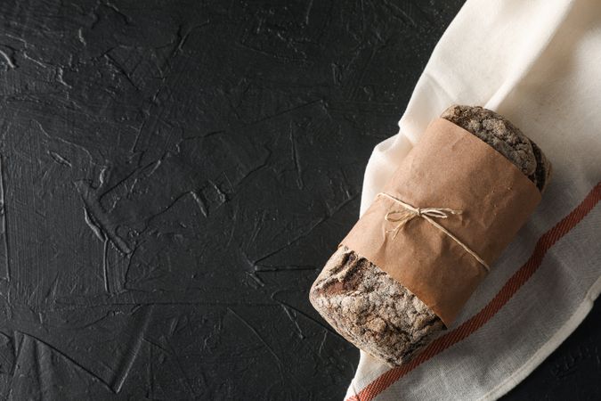 Rye bread on kitchen towel on table against wooden background, space for text and top view