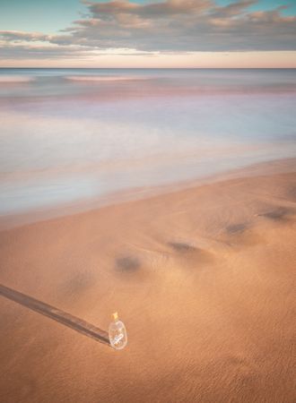 Bottle in sand near sea