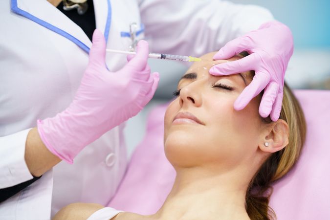 Woman with eyes closed having her face injected
