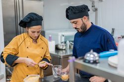 Cook with colleague serving food on plate