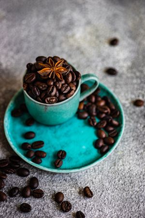 Full teal cup of coffee beans with star anise