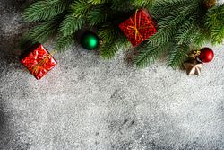 Christmas frame with pine and gift boxes on stone background