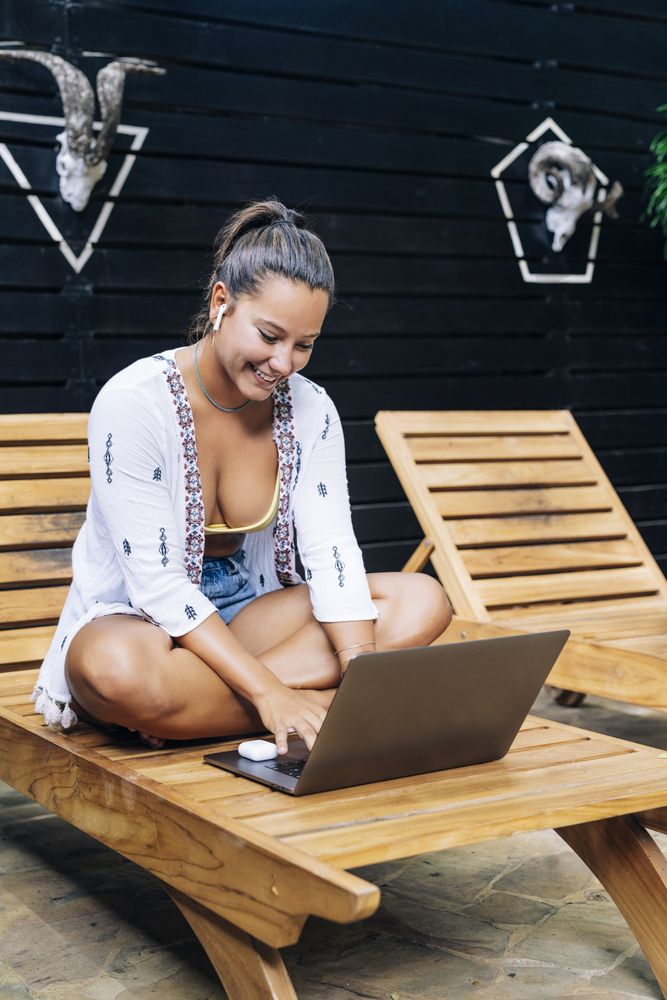 Relaxed woman using laptop while resting on deck chair
