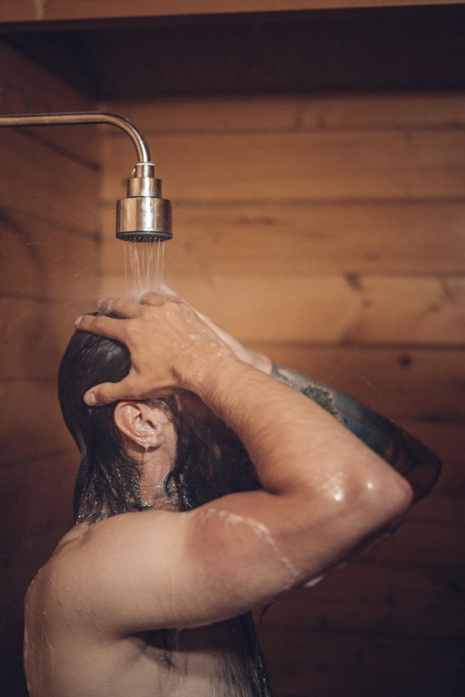 Man taking shower in wooden bathroom