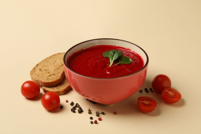 Bowl of tomato soup with ingredients and slices of bread