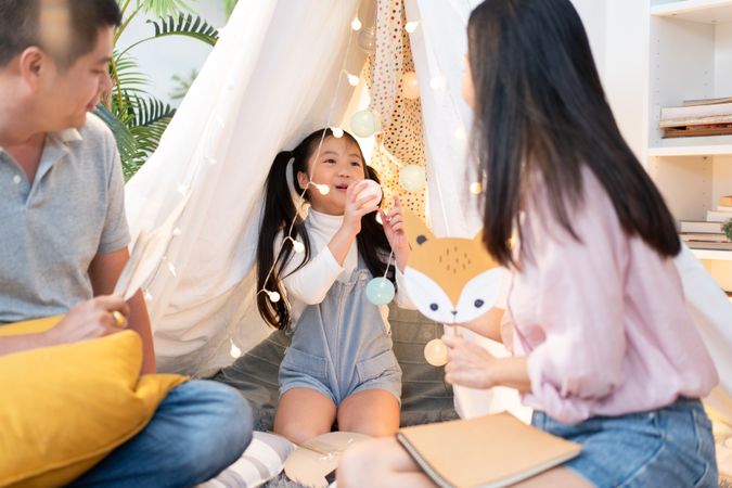 Little girl playing with parent in a cozy tent at home