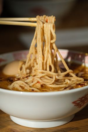 Anonymous person with chopsticks taking noodles from bowl