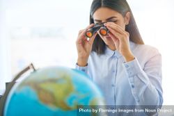 Arab female looking at globe through binoculars 5Qprn0