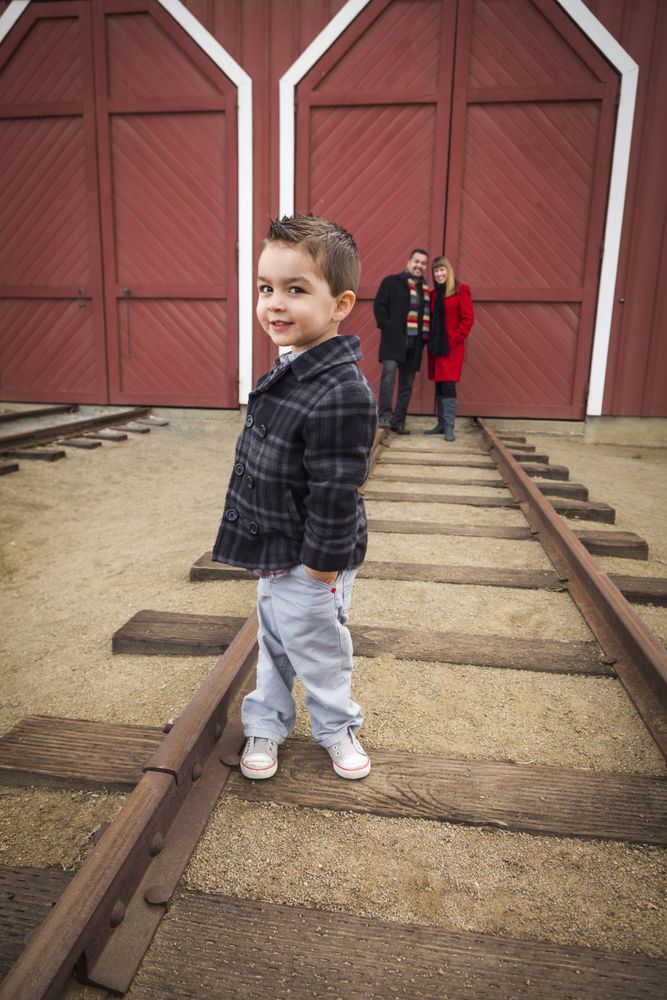 Boy at Train Depot with Parents Smiling Behind