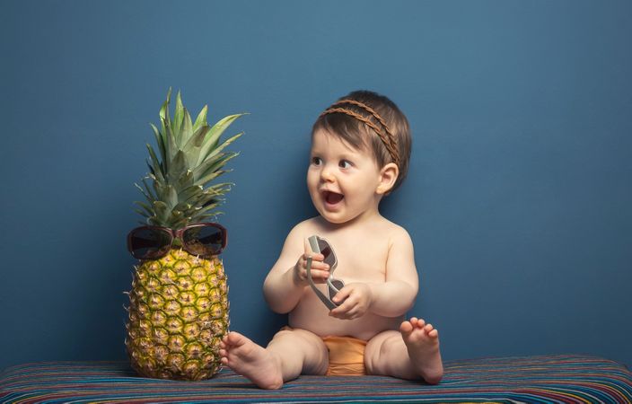 Happy baby playing with a pineapple