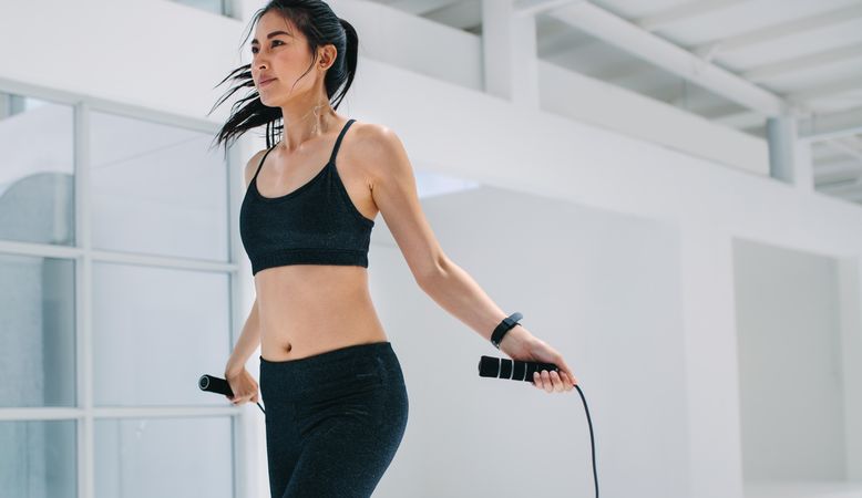 Female doing fitness training with jump rope at health club