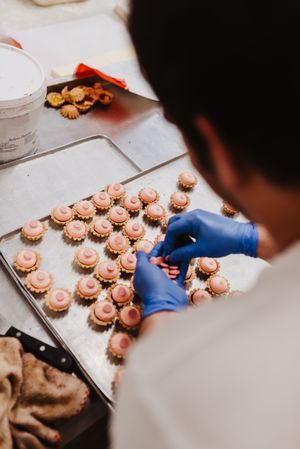 Anonymous baker decorating small cakes