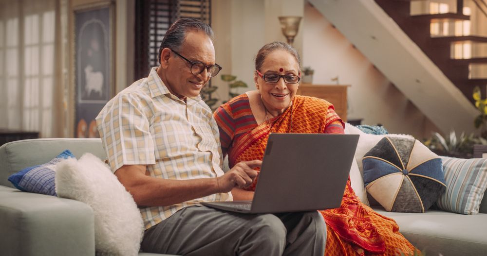 Mature Couple Using Laptop at Home: Exploring New Interests, Discovering Online Communities, and Enriching Their Lives Through Technology.