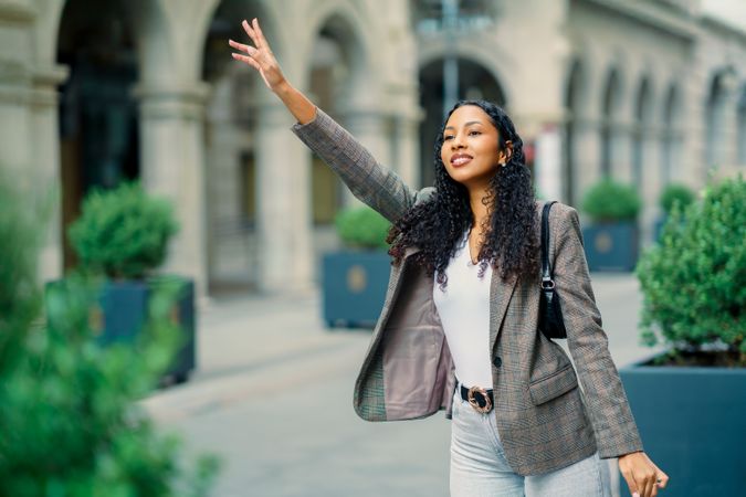 A charming young woman is cheerfully waving in a vibrant urban setting filled with life
