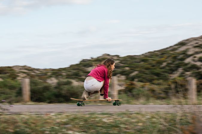 Smiling woman riding longboard on asphalt road