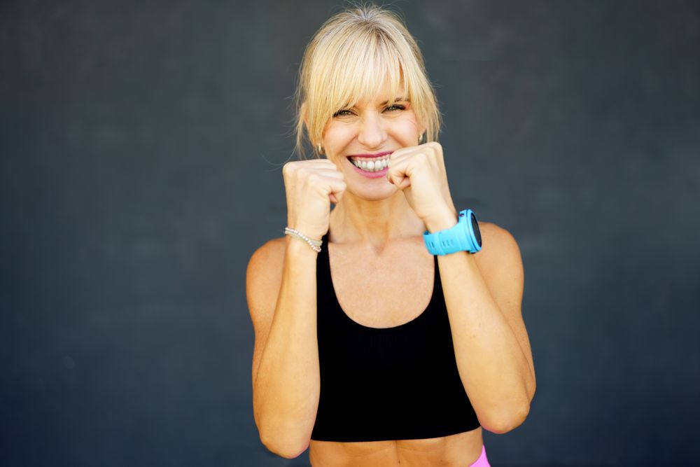Smiling blonde woman making fists for boxing
