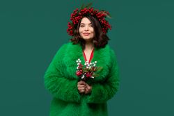 Smiling woman in green coat and red berry wreath
