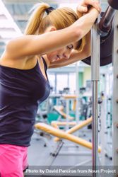 Fit woman leaning on barbell in between lifting 4A1M64