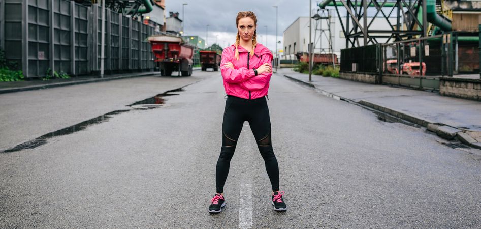 Sporty woman looking camera posing in front of a factory