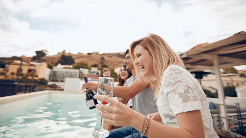 Young people drinking by the pool during party