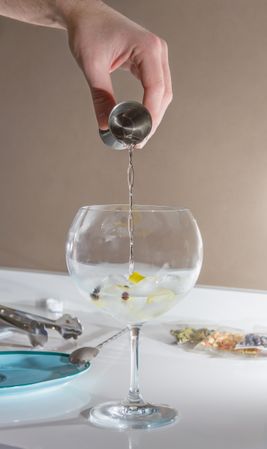 Barman pouring drink to prepare gin tonic cocktail