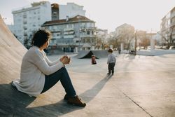 Woman sitting on a skate ramp looking over at her children