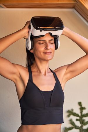 Relaxed young woman taking off VR headset in sunny day