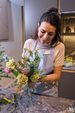 Happy female florist composing bouquet