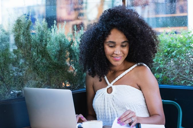 Smiling Black woman working on laptop in cafe
