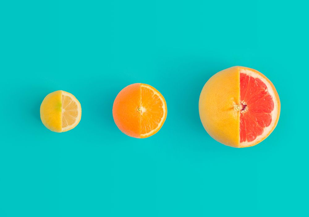 Lemon, orange and grapefruit partially sliced on bright blue background