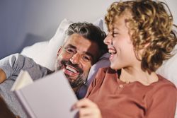 Happy father and son reading on bed