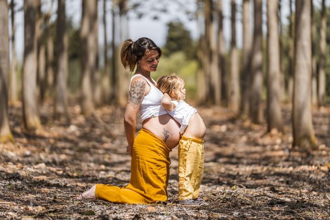 Pregnant mother and little daughter having fun in park